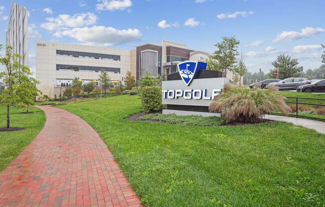 A brick pathway leads to a Topgolf sign in front of a building.