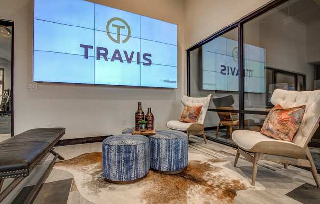 a lounge area with two chairs and a table with two bottles of wine on it