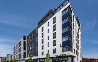 A modern multi-story building with a black car parked in front.