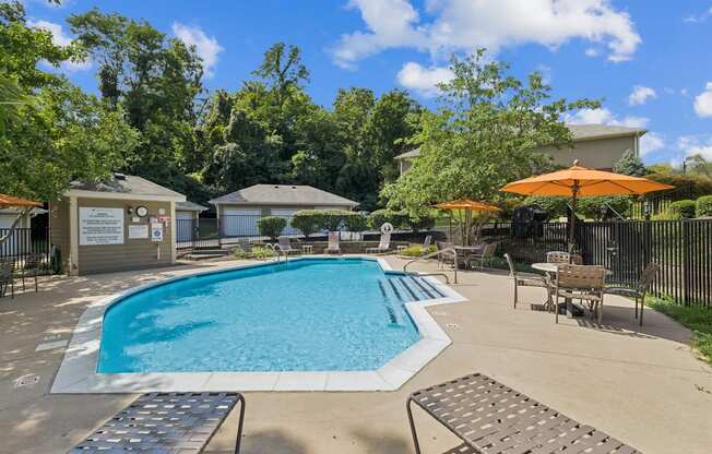 A pool surrounded by trees and a building in the background.