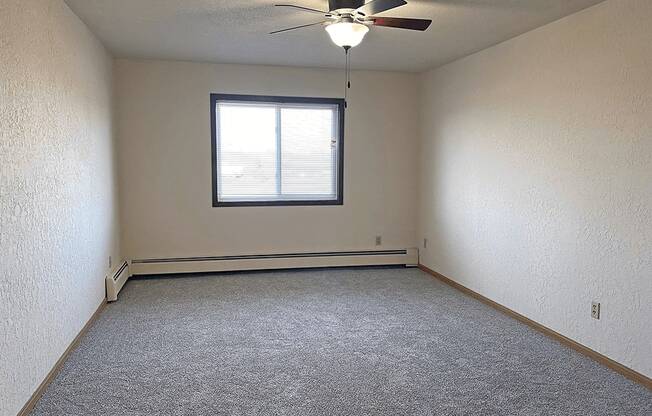 an empty room with a ceiling fan and a window