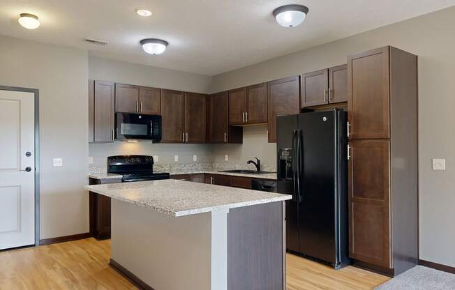 a kitchen with dark cabinets, black appliances, and light granite countertops