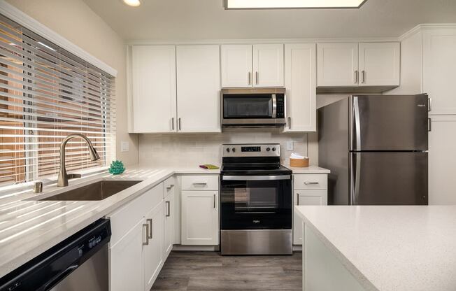 Apartments for Rent Oceanside CA - Stone Arbor - White Kitchen with Wood-Style Flooring and Stainless Steel Appliances