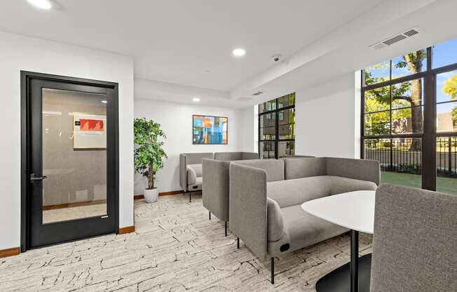A modern waiting room with grey couches and a black table.