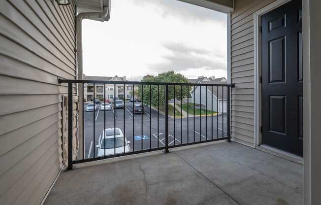 a balcony with a black railing and a parking lot in the background