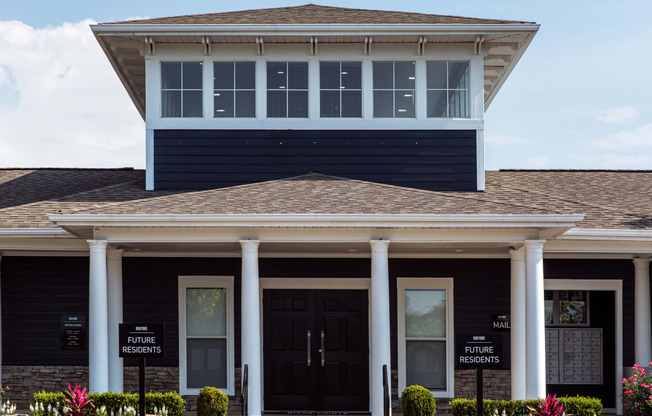 the front of a house with two black doors and two white columns