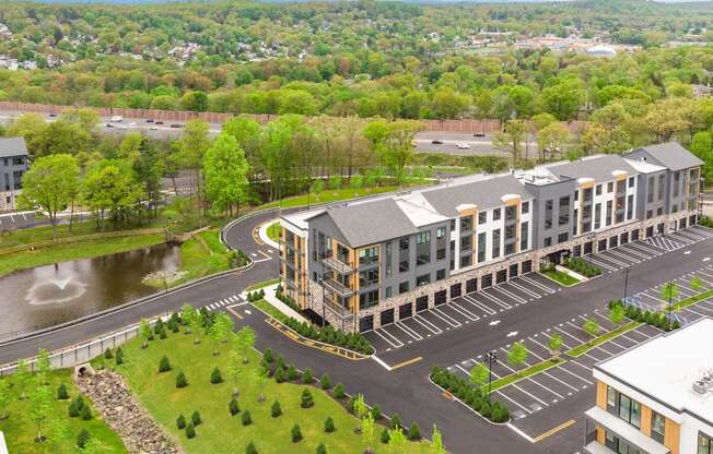 an aerial view of an apartment building with a parking lot and a river