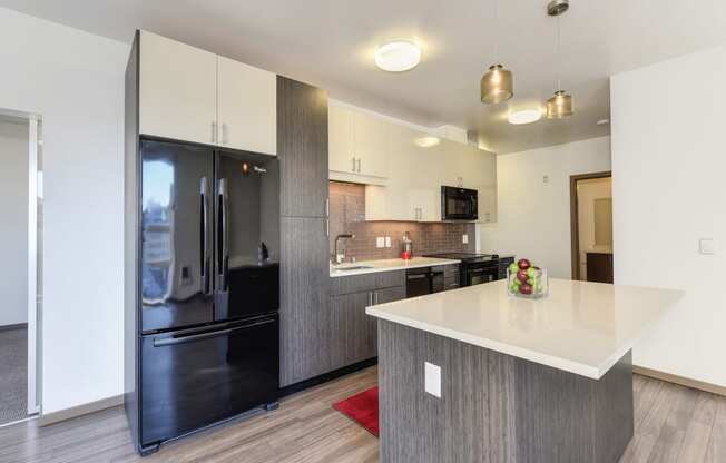 Kitchen with Hardwood Inspired Floor, Refrigerator, Gray Cabinents, Microwave and Bowl of Green/Red Apples