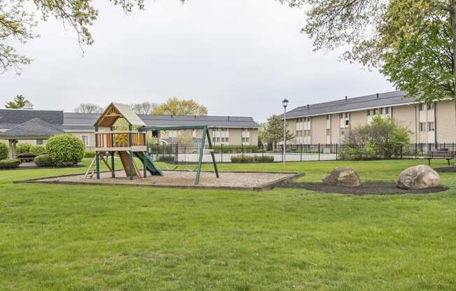 a playground with a wooden swing set in the middle of a grassy area