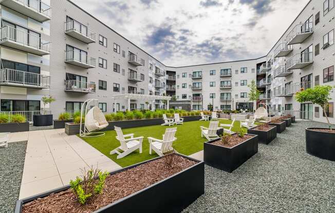 an open courtyard with chairs and tables in front of an apartment building