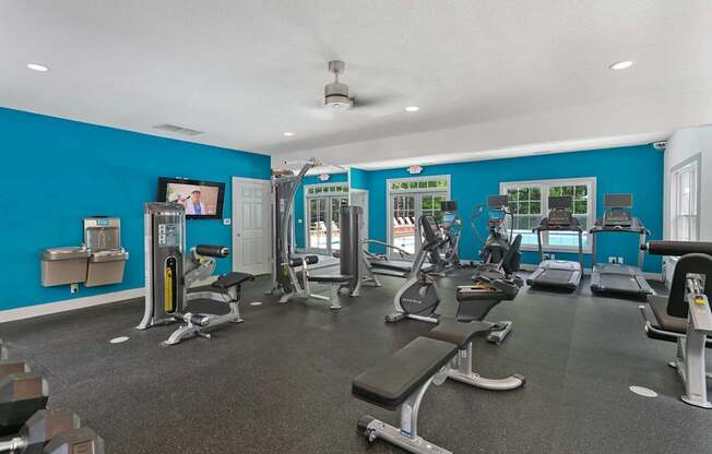 A gym with a variety of equipment including treadmills, weights, and exercise machines.