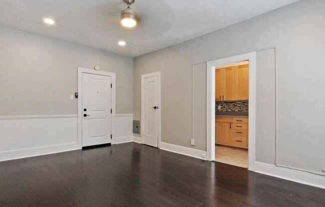 A studio apartment in Pasadena, CA with white walls and a wooden floor with a door and a window at Brookmore Apartments.