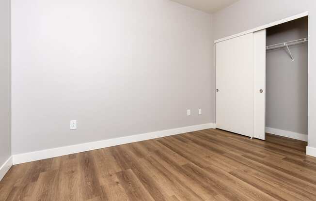 an empty room with a closet and wood flooring