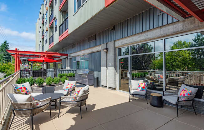 A patio with chairs and a table with a red umbrella.