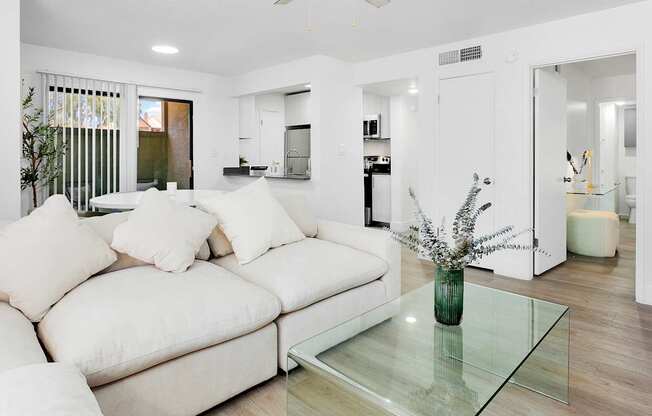 A modern living room with a white couch and a glass coffee table.