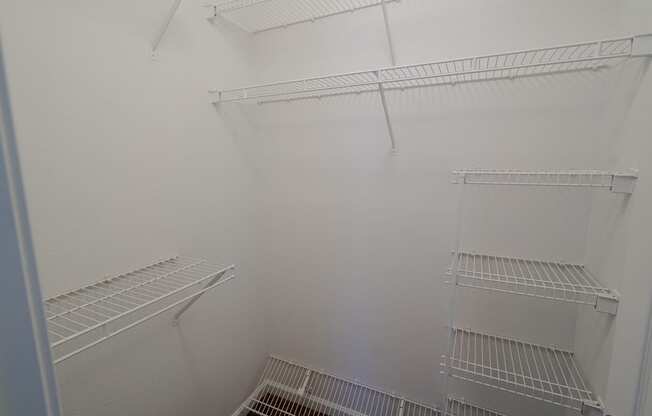 a walk in closet with white walls and shelves