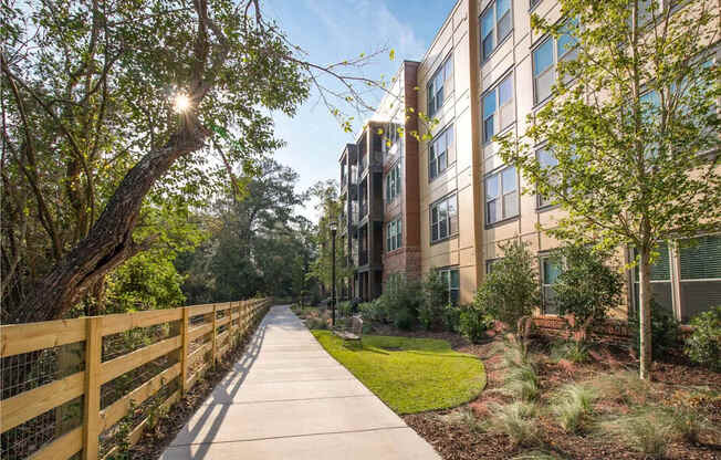 A wooden fence runs along a sidewalk in front of a building.