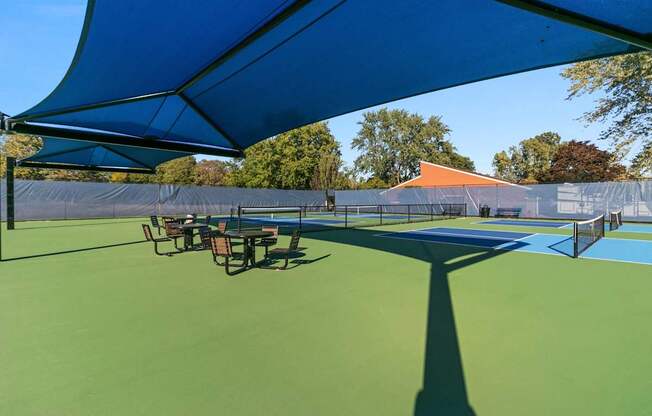 A tennis court with a blue canopy and green surface.