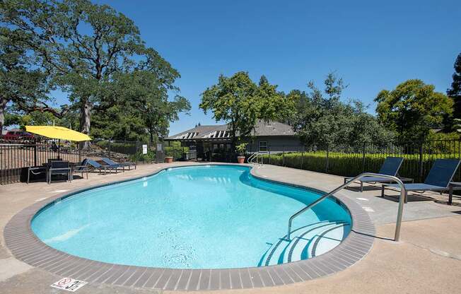 A round swimming pool surrounded by trees and chairs at Rocklin Gold Apartments, California, 95677