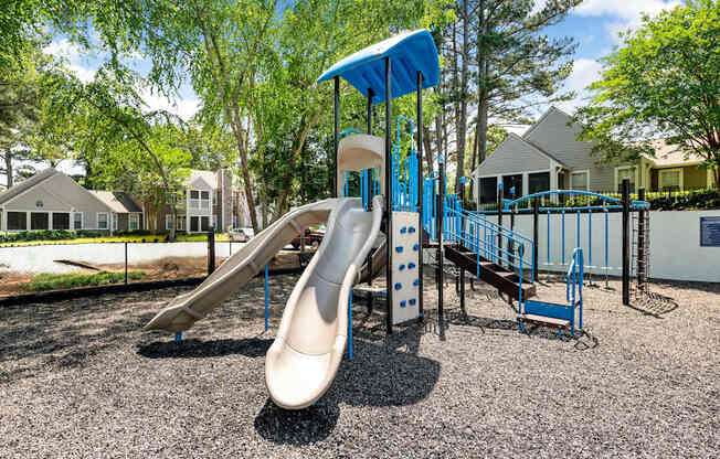 A playground with a slide and a blue canopy.