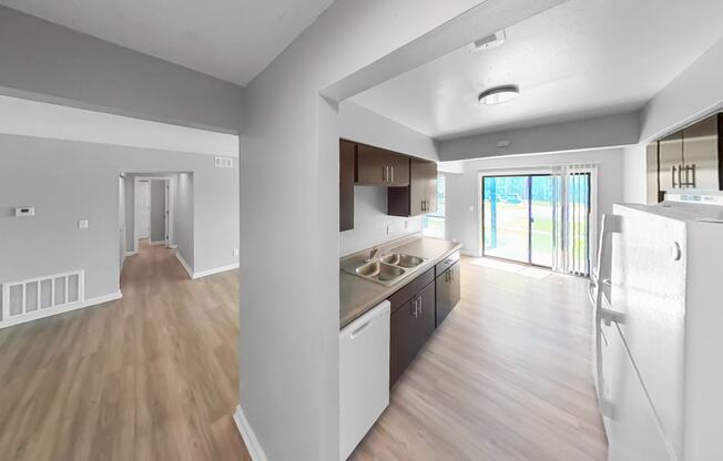 an open kitchen and living room with wood flooring and a door to a balcony