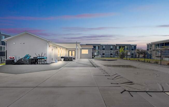 A parking lot with a white building and a black fence.