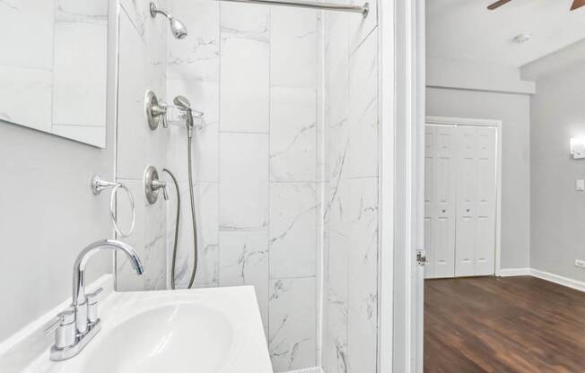 A white sink with a silver faucet in a marble tiled bathroom.