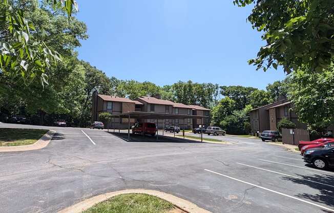 a parking lot in front of a apartment building with cars parked in the parking lot