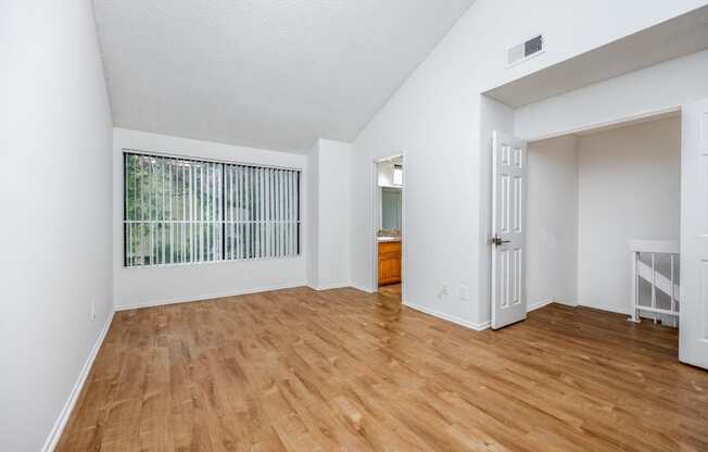 an empty living room with wood flooring and a large window