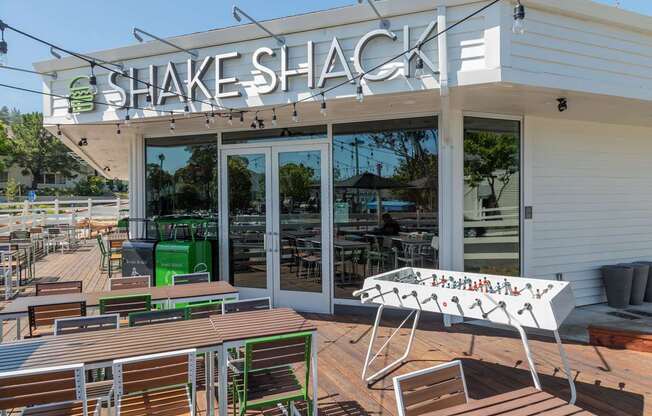 A Shake Shack restaurant with a green trash can and a white table.