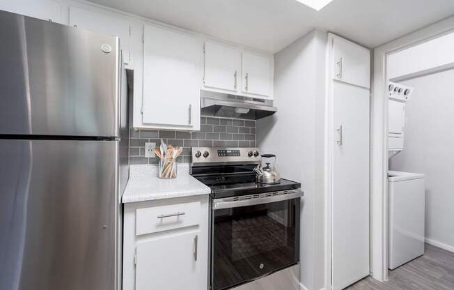 A modern kitchen with a stainless steel refrigerator and white cabinets.