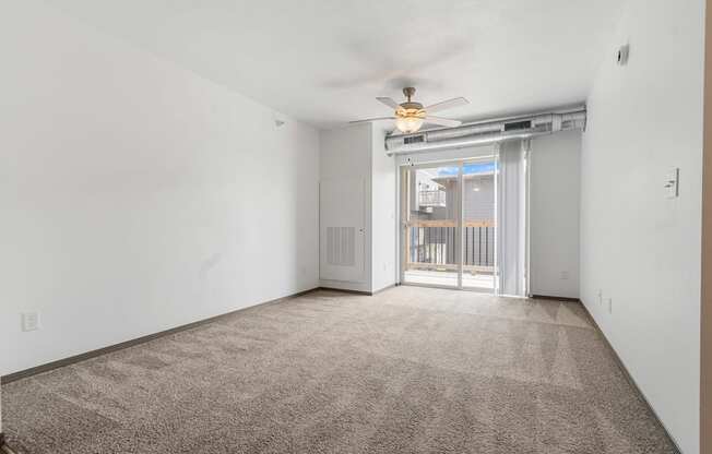 A room with a carpet floor and a ceiling fan.