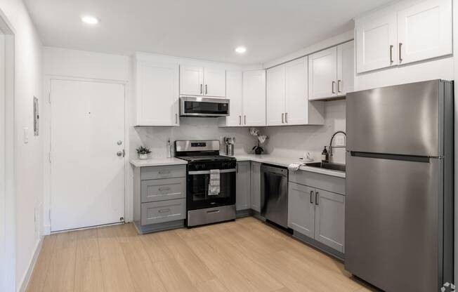 a renovated kitchen with stainless steel appliances and white cabinets