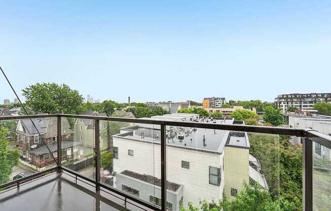 A balcony overlooks a residential area with houses and trees.