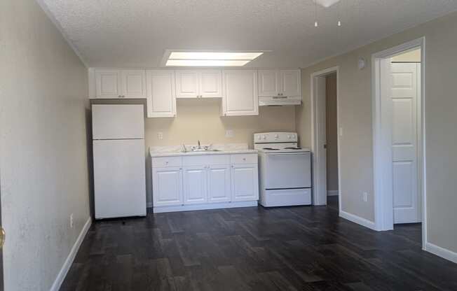 an empty kitchen with white cabinets and a ceiling fan