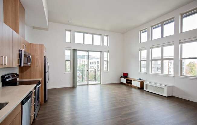 a living room with a large window and a kitchen with wood floors