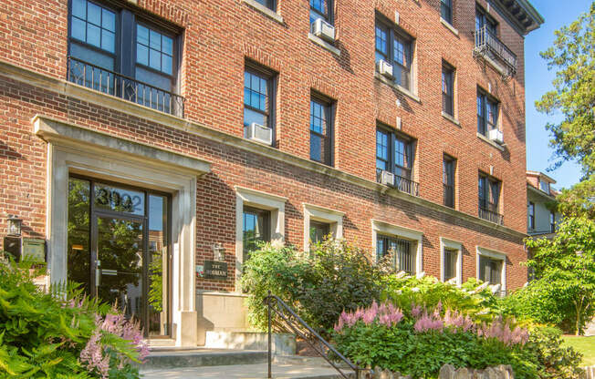 the front of a brick building with stairs and plants