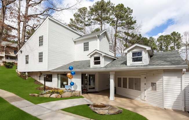 A white house with a grey roof and a balloon arch on the front door.