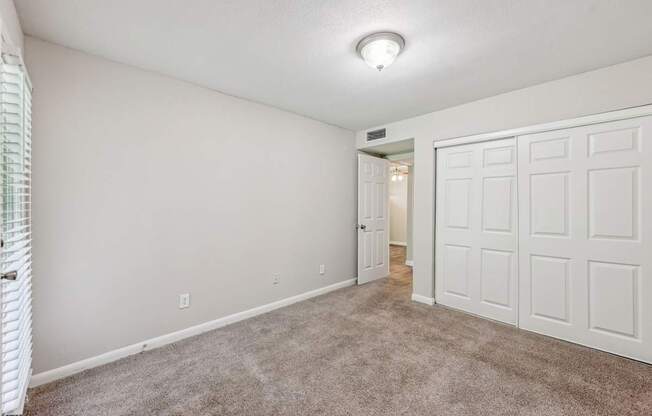 A bedroom with a closet and carpet at Gwinnett Square Apartments in Duluth, GA