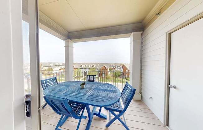 A blue table and chairs are on a porch.