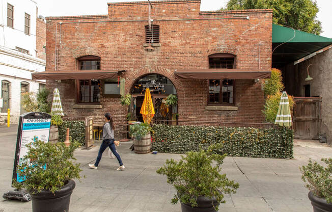 a woman walks past a brick building with a green awning