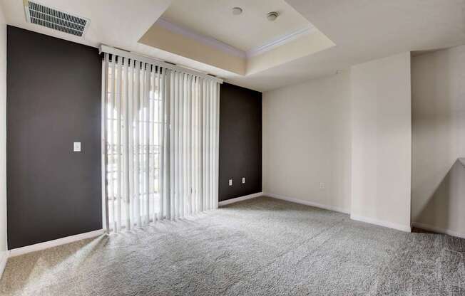 A room with a carpeted floor and a window with blinds.