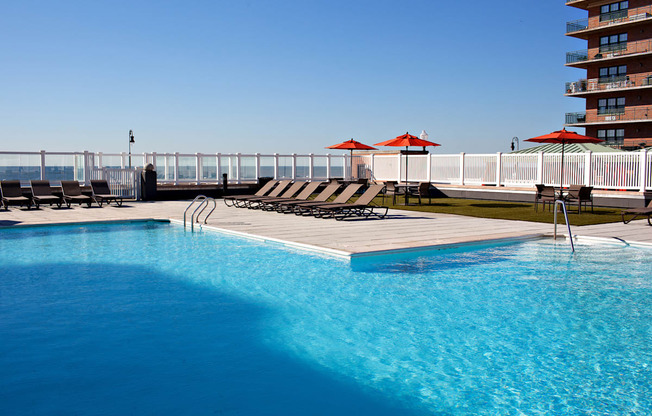 a swimming pool with chairs and umbrellas next to a hotel