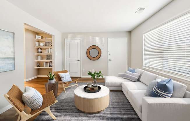 A living room with a white couch, a wooden coffee table, and a painting on the wall.