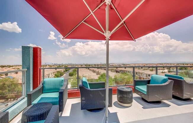 A patio with a red umbrella and several chairs.