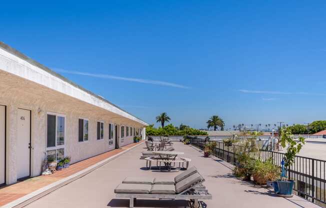 the terrace of a building with tables and chairs and the ocean in the background