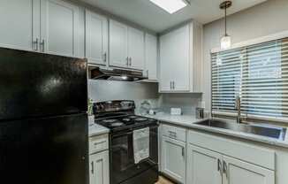 Kitchen with Black Appliances, Grey Cabinets, and Wood-Style Flooring at Aspire Upland Apartments, Upland