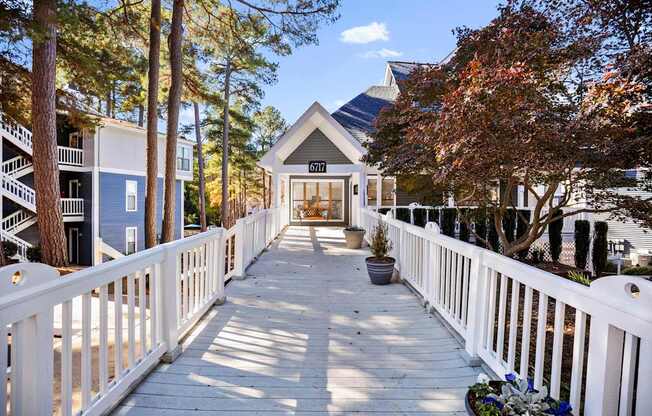 A white fence leads to a building with a balcony.