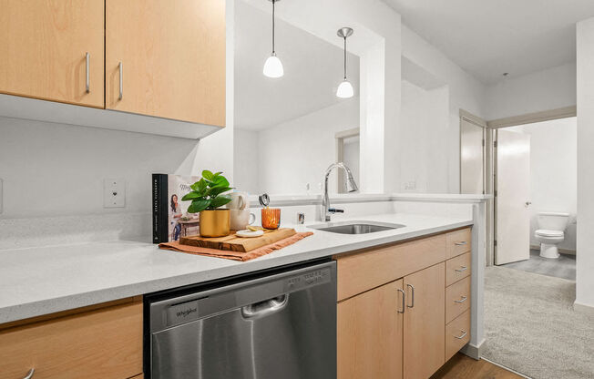 A modern kitchen with wooden cabinets and a stainless steel dishwasher.