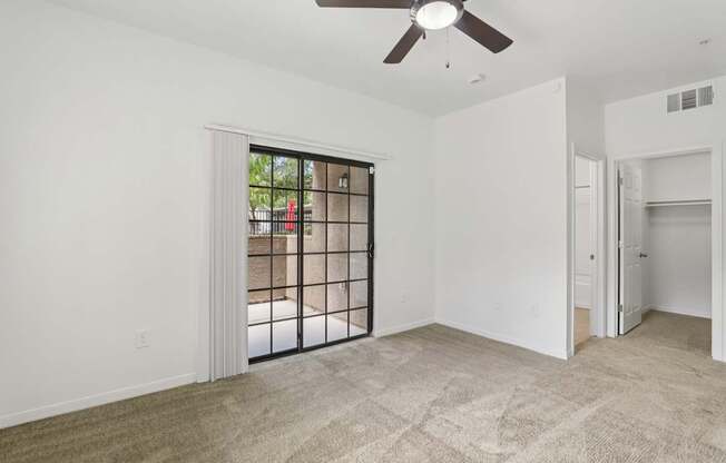 A room with a ceiling fan and a sliding glass door leading outside.